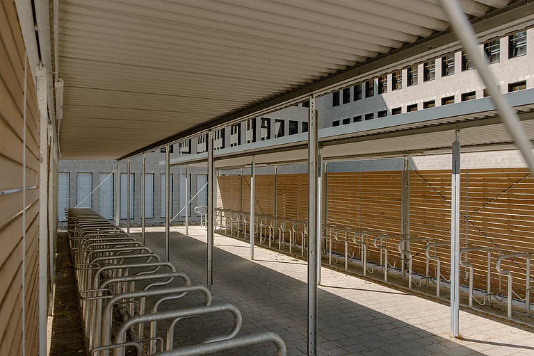 Das Foto zeigt einen überdachten Fahrradständer auf dem Schulhof hinter dem E-Gebäude.