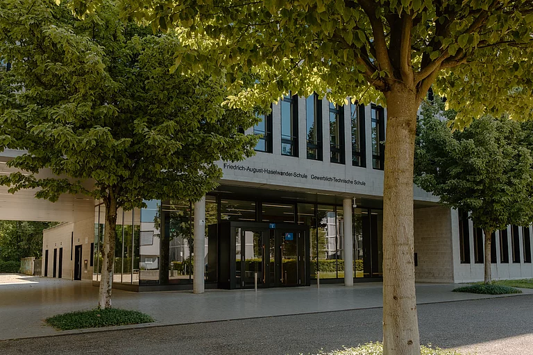Das Foto zeigt das G-Gebäude der Schule. Man blickt auf den Haupteingang unseres Verwaltungsgebäudes, in dem sich das Sekretariat befindet. Die Ansicht ist von der Friedenstraße kommend aufgenommen.
