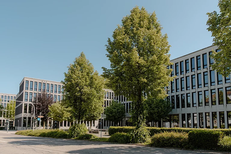 Das Foto zeigt die Hauptansicht auf den Gebäudekomplex der Schule. In der Flucht sieht man zunächst das G-Gebäude, dann das F-Gebäude und klein im Hintergrund ein Stück des E-Gebäudes.
