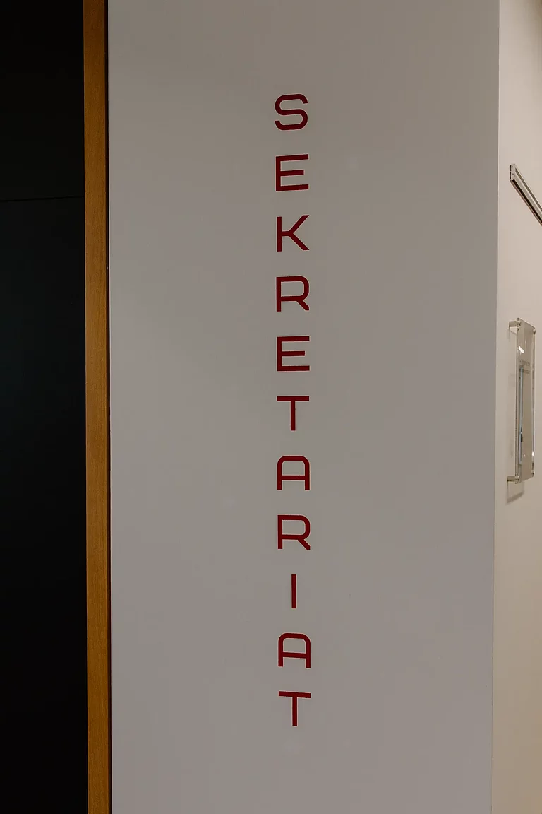 Das Foto zeigt den Schriftzug "Sekretariat", der sich rechts neben dem Eingang zum Schülersekretariat befindet.