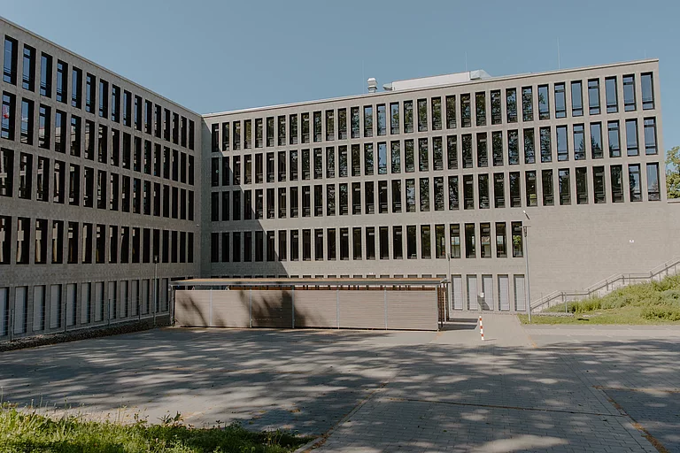 Das Foto zeigt die Ansicht der E-Gebäudes und des davorliegenden Schulhofes mit Schülerparkplätzen und Fahrradständer.