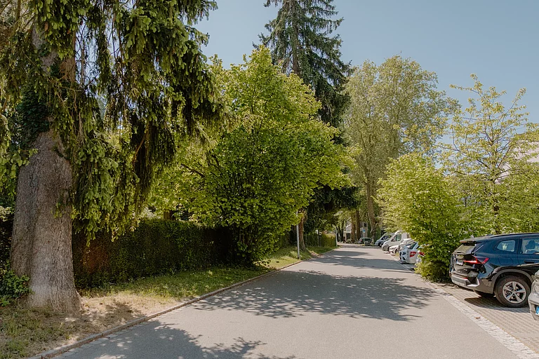 Das Foto zeigt die Sackgasse, die zwischen Schulgebäude und Friedhof entlangführt. Hier finden sich kostenfreie Parkplätze.
