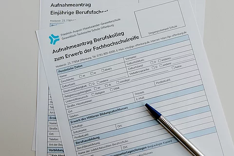 Das Foto zeigt ein Anmeldeformular der Schule und einen Kugelschreiber.