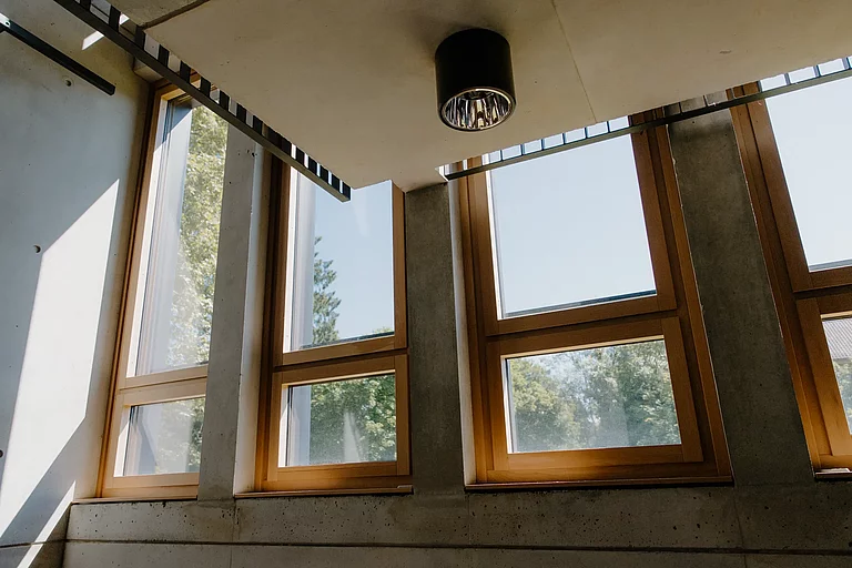 Das Foto zeigt eine Detailaufnahme aus einem Treppenhaus im G-Gebäude. Man sieht lichtdurchflutete große Fenster.
