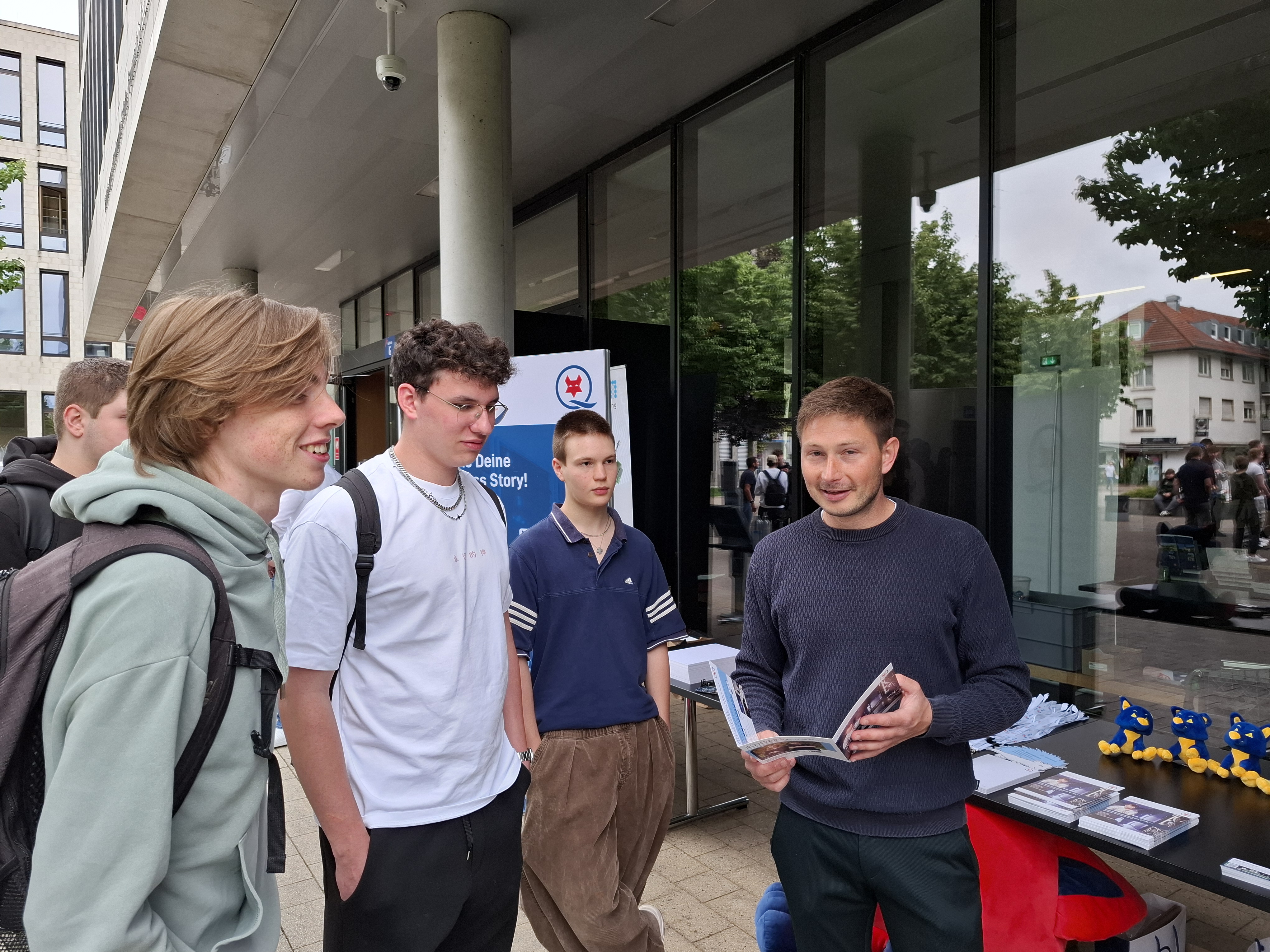 Das Foto zeigt Schüler, die auf dem Schulhof einen Stand der Berufsinfomesse besuchen.